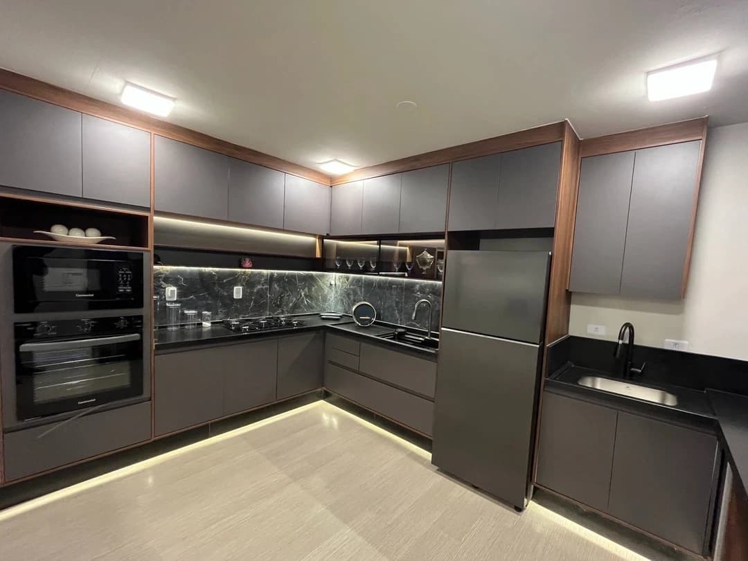 Cozinha Moderna e Funcional: Cozinha com design contemporâneo, predominância de tons cinza e acabamentos em madeira. Funcionalidade e iluminação embutida destacam o ambiente.
