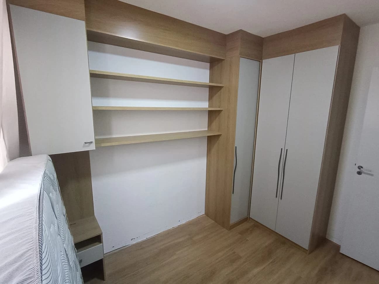 Quarto Moderno com Armário Planejado: Ambiente contemporâneo em tons neutros, com armário em madeira clara e prateleiras funcionais. Projetado para otimizar espaço e trazer praticidade.