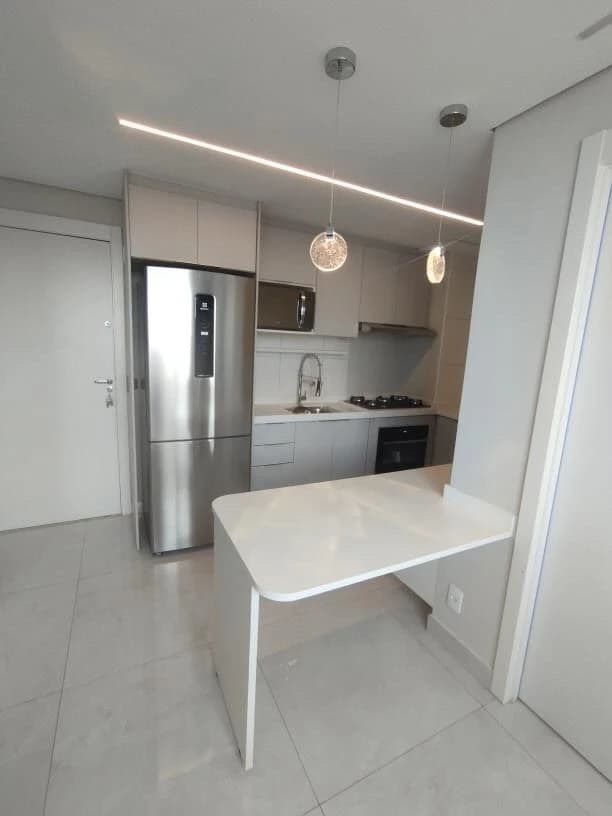 Cozinha Moderna e Funcional: Ambiente em tons neutros com móveis planejados e iluminação pendente. Superfícies em aço inox e granito, ideal para otimização de espaço e praticidade.