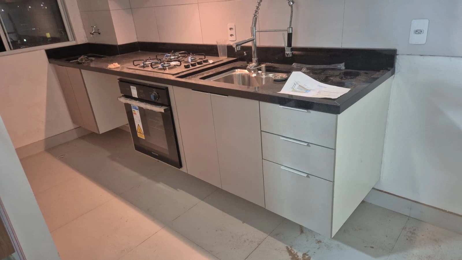 Cozinha Moderna e Funcional: Ambiente clean com armários em MDF, bancada em granito escuro e eletrodomésticos inox. Estilo contemporâneo que prioriza a praticidade e estética.