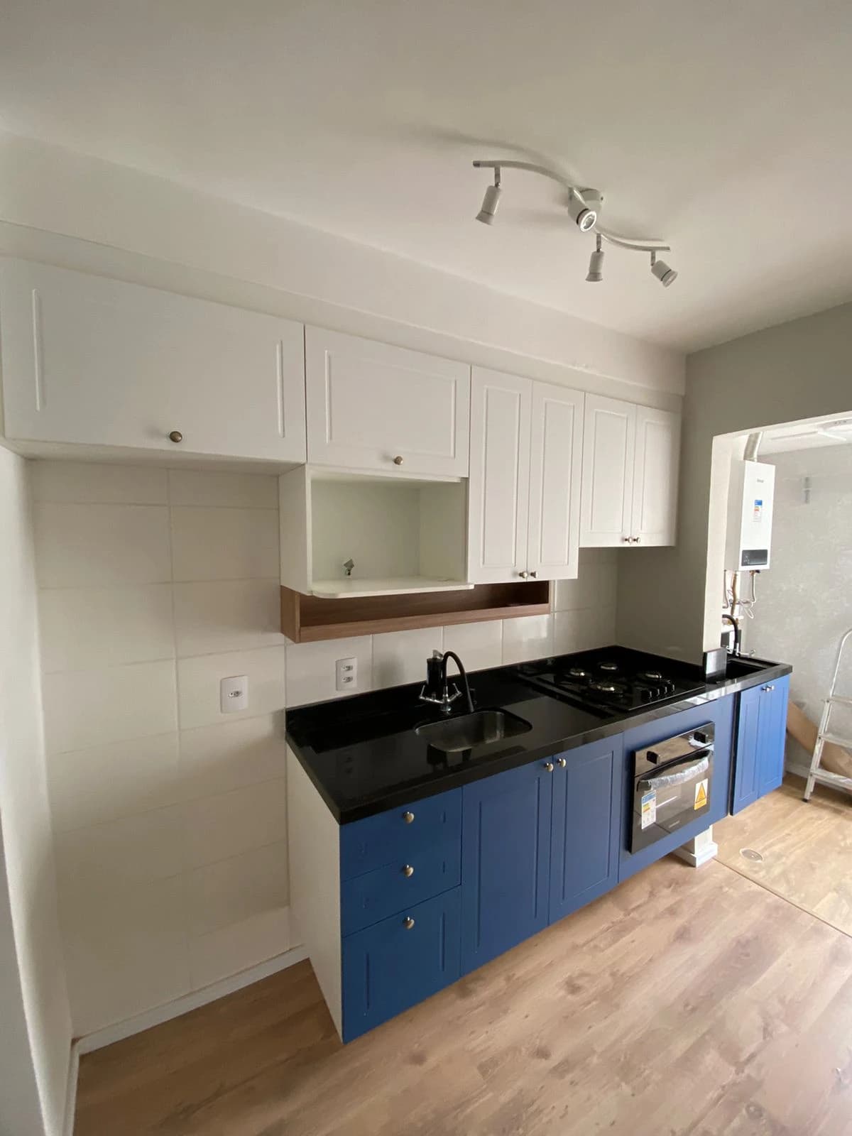 Cozinha Moderna com Toques de Cor: Cozinha em estilo moderno, com armários brancos e detalhes em azul. A bancada de granito preto destaca a funcionalidade do espaço, ideal para refeições rápidas.